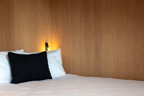 Hotel bed with pillows next to a wooden wall