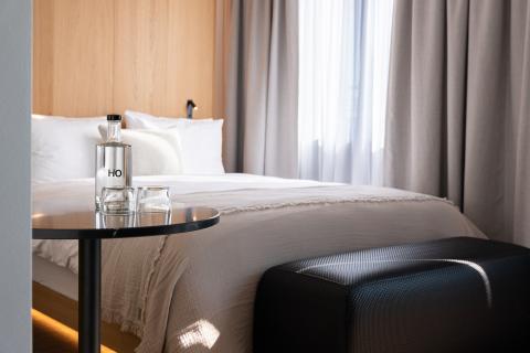 Hotel bed with a black side table and a water bottle