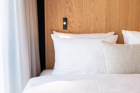 Double bed with wooden wall next to a window in Schwabing hotel