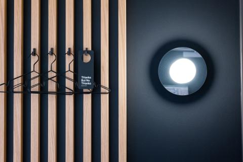 Hotel room wardrobe with black hangers and a wooden wall