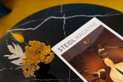 Details of a magazine and flowers on a round black marble table