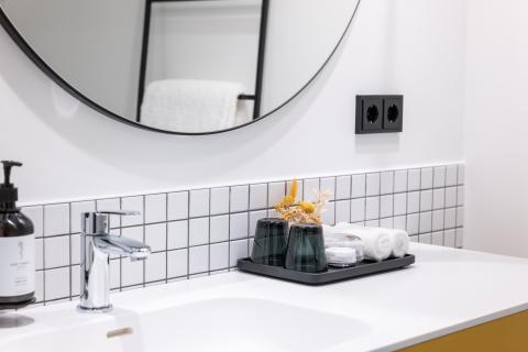 Hotel room bathroom sink with big mirror, towels and soap